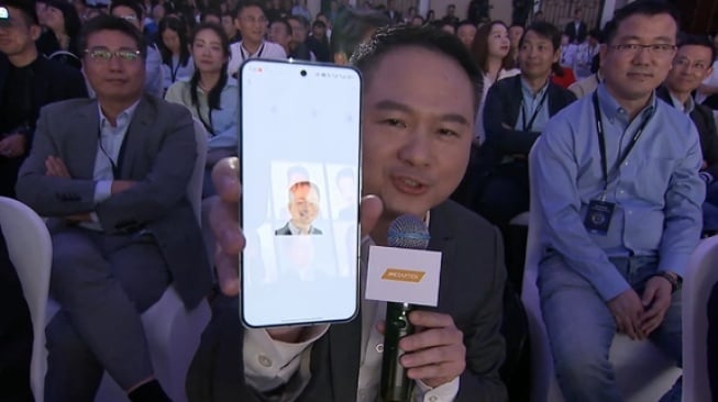 Zeng Xuezhong, Wakil Presiden Senior Grup Xiaomi dan Presiden Departemen Ponsel, memegang smartphone diduga Redmi K70. [CNMO]