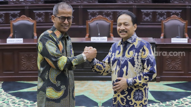 Ketua Mahkamah Konstitusi yang baru, Suhartoyo (kanan) berjabat tangan dengan Wakil Ketua MK Saldi Isra (kiri) saat konferensi pers di Gedung MK, Jakarta, Kamis (9/11/2023). [Suara.com/Alfian Winanto]