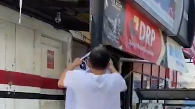 Tangkapan layar seorang pria menurunkan poster bergambar muka Ganjar Pranowo di Sumut.