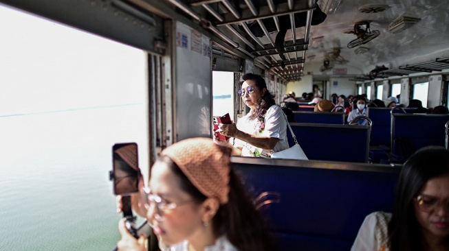 Wisatawan mengabadikan pemandangan saat menaiki wisata "Kereta Apung" yang tengan melintas di Bendungan Pasak Jolasid, Provinsi Lopburi, Thailand, Sabtu (4/11/2023). [MANAN VATSYAYANA / AFP]