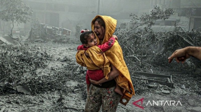 Seorang wanita menggendong seorang gadis bereaksi setelah serangan udara Israel menghantam lingkungan Ridwan di Kota Gaza, Gaza pada 23 Oktober 2023. (ANTARA/Ali Jadallah / Anadolu/pri.)