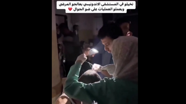 Potret korban serangan Israel di Gaza yang dioperasi di koridor RS Indonesia dengan bantuan lampu senter HP dan tanpa obat bius. (Twitter/@QudsNen)