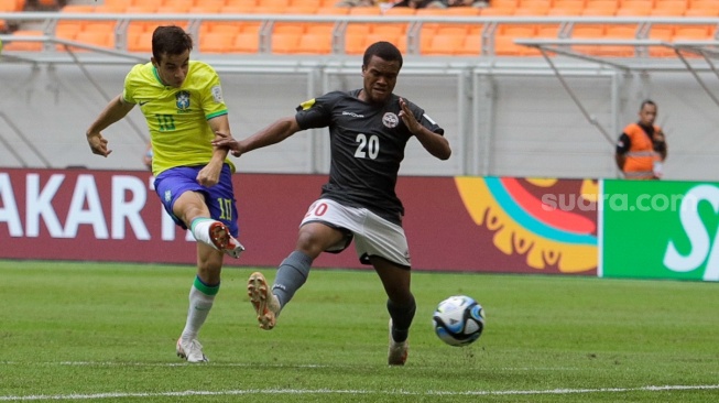 Pesepak bola Timnas Brasil U-17 Dudu menendang bola melewati pemain Timnas Kaledonia Baru U-17 Qaeze Paul pada pertandingan Grup C Piala Dunia U-17 2023 di tempat Jakarta International Stadium (JIS), Jakarta, Selasa (14/11/2023). [Suara.com/Alfian Winanto]