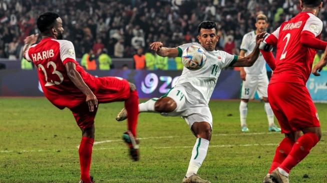 Gelandang timnas Irak Amjad Attwan (tengah) menendang bola pada pertandinganfinal Piala Teluk Arab ke-25 antara Irak vs Oman di Stadion Internasional Basra di kota selatan Irak pada 19 Januari 2023. AHMAD AL-RUBAYE / AFP.