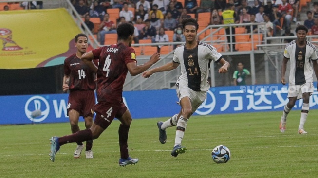 Pesepak bola Timnas Jerman U-17 David Odogu berusaha melewati pemain Timnas Venezuela U-17 pada pertandingan Grup F Piala Dunia U-17 2023 di Jakarta International Stadium (JIS), Jakarta, Sabtu (18/11/2023). [Suara.com/Alfian Winanto]