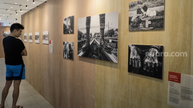 Pengunjung melihat karya yang dipamerkan di Pameran Foto Rekam Jakarta 2023 Masa ke Massa di Galeri Emiria Soenassa, Taman Ismail Marzuki (TIM), Jakarta, Selasa (21/11/2023). [Suara.com/Alfian Winanto]