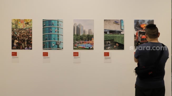 Pengunjung melihat karya yang dipamerkan di Pameran Foto Rekam Jakarta 2023 Masa ke Massa di Galeri Emiria Soenassa, Taman Ismail Marzuki (TIM), Jakarta, Selasa (21/11/2023). [Suara.com/Alfian Winanto]