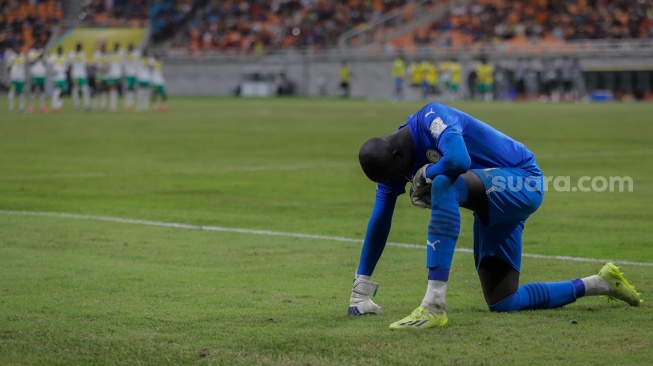 Penjaga gawang Timnas Senegal U-17 Serigne Diouf berdoa saat melawan Timnas Prancis U-17 dalam babak adu penalti pada pertandingan babak 16 besar Piala Dunia U-17 2023 di Jakarta International Stadium (JIS), Jakarta, Rabu (22/11/2023). [Suara.com/Alfian Winanto]

