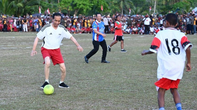 Presiden Joko Widodo atau Jokowi menggiring bola saat bermain sepak bola dengan pelajar di Lapangan Sepak Bola Sorido, Kabupaten Biak Numfor, Provinsi Papua, pada Rabu (22/11/2023). [Foto: Kris - Biro Pers Sekretariat Presiden]