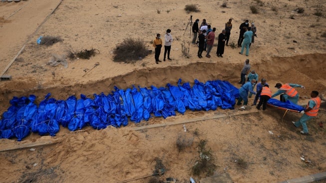 Petugas menguburkan jenazah warga Palestina di kuburan massal di pemakaman Khan Yunis, Gaza selatan, Rabu (22/11/2023). [Mahmud HAMS/AFP]