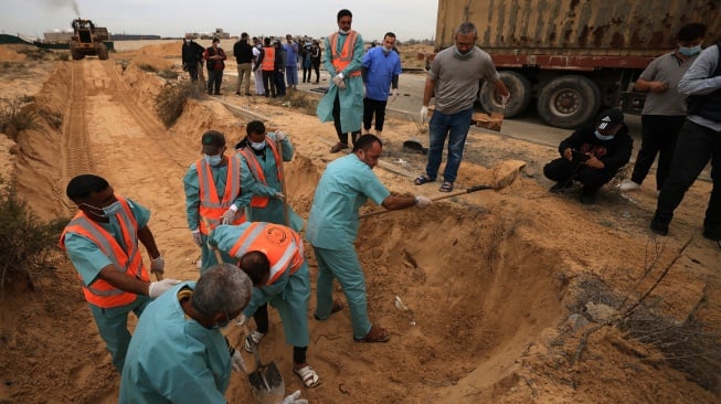 Petugas menguburkan jenazah warga Palestina di kuburan massal di pemakaman Khan Yunis, Gaza selatan, Rabu (22/11/2023). [Mahmud HAMS/AFP]