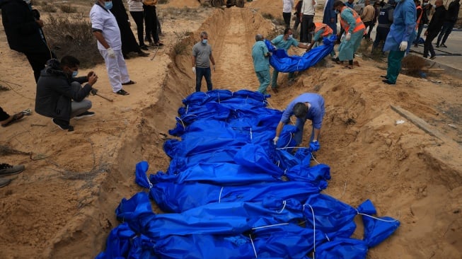 Petugas menguburkan jenazah warga Palestina di kuburan massal di pemakaman Khan Yunis, Gaza selatan, Rabu (22/11/2023). [Mahmud HAMS/AFP]