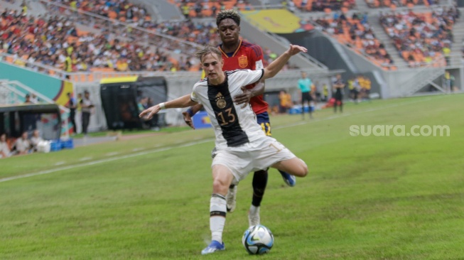 Pesepak bola Timnas Jerman U-17 Maximilian Henning berebut bola dengan pemain Timnas Spanyol U-17 Igor Oyono pada pertandingan babak Perempat Final Piala Dunia U-17 2023 di Jakarta International Stadium (JIS), Jakarta, Jumat (24/11/2023). [Suara.com/Alfian Winanto]
 