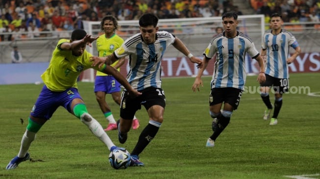 Pesepak bola Timnas Brasil U-17 Kaua Elias berebut bola dengan pemain Timnas Argentina U-17 Tobias Palacio pada pertandingan babak Perempat Final Piala Dunia U-17 2023 di Jakarta International Stadium (JIS), Jakarta, Jumat (24/11/2023). [Suara.com/Alfian Winanto]