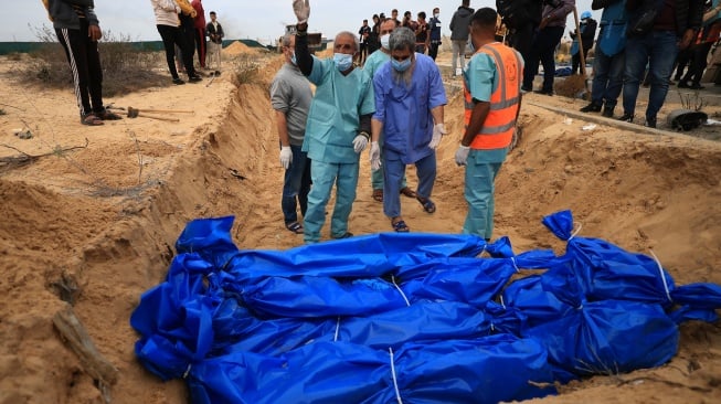 Petugas menguburkan jenazah warga Palestina di kuburan massal di pemakaman Khan Yunis, Gaza selatan, Rabu (22/11/2023). [Mahmud HAMS/AFP]