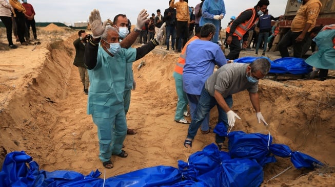 Petugas menguburkan jenazah warga Palestina di kuburan massal di pemakaman Khan Yunis, Gaza selatan, Rabu (22/11/2023). [Mahmud HAMS/AFP]