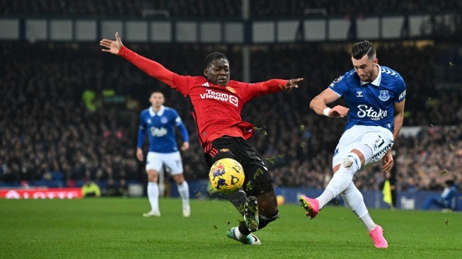 Gelandang Manchester United, Kobbie Mainoo (kiri) berebut bola pada laga Liga Inggris kontra Everton di Goodison Park, Liverpool yang rampung Senin (27/11) dini hari WIB. [PAUL ELLIS / AFP]