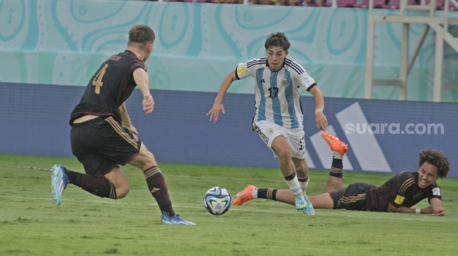 Gelandang Timnas Argentina U-17, Valentino Acuna melewati adangan dua pemain Jerman dalam laga semifinal Piala Dunia U-17 2023 di Stadion Manahan, Solo, Selasa (28/11/2023). [Suara.com/Ronald Seger Prabowo]