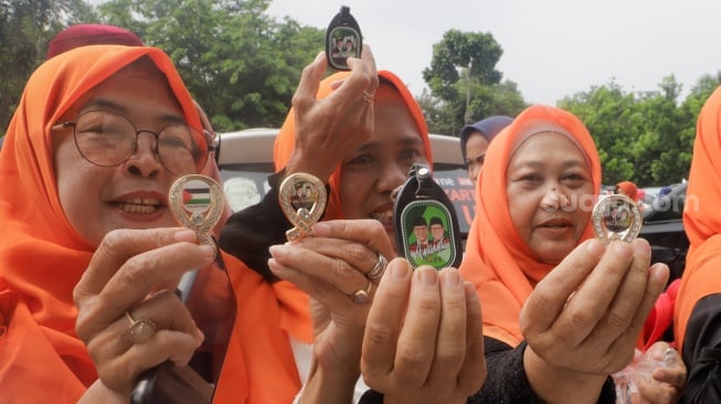 Pendukung menunjukkan aksesoris bergambar Capres dan Cawapres nomor urut 1 Anies Baswedan dan Muhaimin Iskandar saat menghadiri kampanye perdana di GOR Ciracas, Jakarta, Selasa (28/11/2023). [Suara.com/Alfian Winanto]