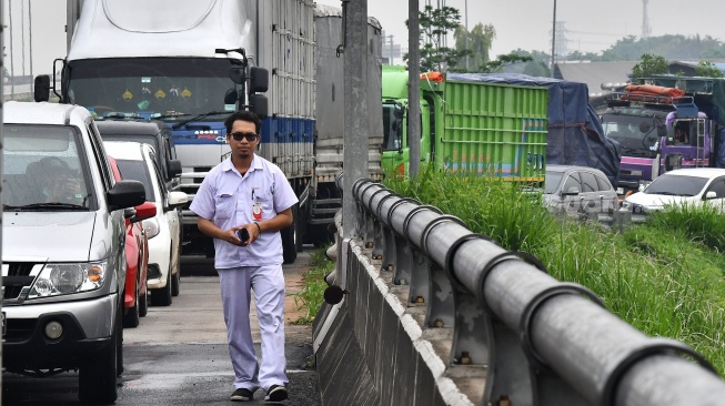 Seorang pekerja berjalan kaki untuk menuju kawasan MM 2100 saat aksi buruh di Kabupaten Bekasi, Jawa Barat, Kamis (30/11/2023). [ANTARA FOTO/ Fakhri Hermansyah/rwa]