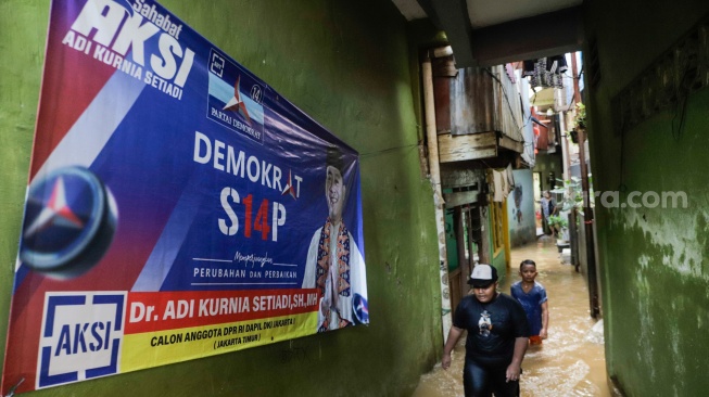 Warga melintasi banjir yang melanda di kawasan Kebon Pala, Kampung Melayu, Jakarta, Kamis (30/11/2023). [Suara.com/Alfian Winanto]