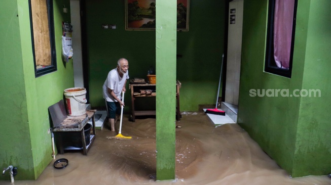 Warga membersihkan lumpur saat banjir melanda di kawasan Kebon Pala, Kampung Melayu, Jakarta, Kamis (30/11/2023). [Suara.com/Alfian Winanto]