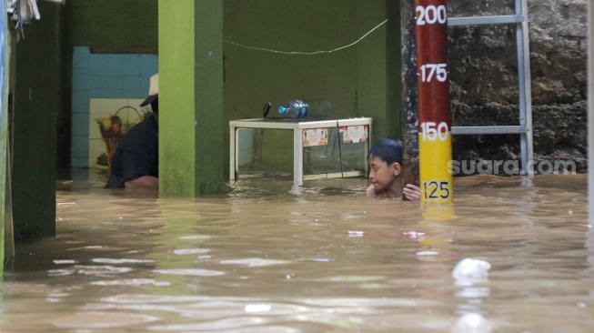 Anak-anak bermain air saat banjir melanda di kawasan Kebon Pala, Kampung Melayu, Jakarta, Kamis (30/11/2023). [Suara.com/Alfian Winanto]