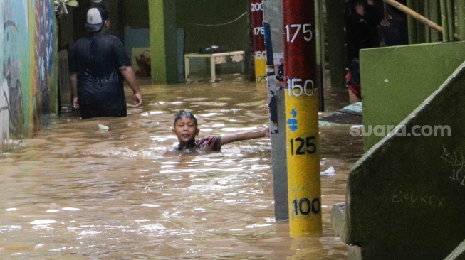 Anak-anak bermain air saat banjir melanda di kawasan Kebon Pala, Kampung Melayu, Jakarta, Kamis (30/11/2023). [Suara.com/Alfian Winanto]