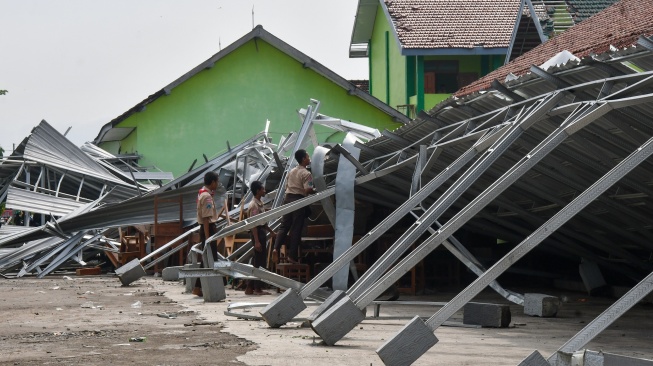 Sejumlah siswa melihat kondisi bangunan tempat parkir yang roboh di SMKN 1 Mejayan akibat bencana puting beliung di Mejayan, Kabupaten Madiun, Jawa Timur, Jumat (1/12/2023). [ANTARA FOTO/Siswowidodo/foc]