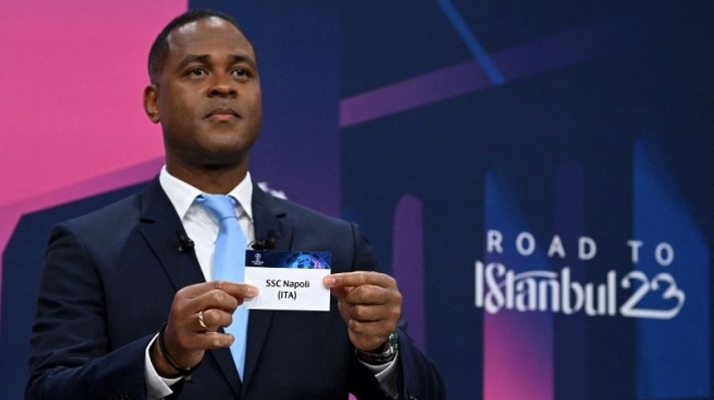 Arsip - Duta final Liga Champions UEFA yang merupakan mantan pemain timnas Belanda Patrick Kluivert memperlihatkan kertas bertuliskan Napoli pada undian perempat final, semifinal, dan final Liga Champions 2022/2023 di Nyon, Prancis, 17 Maret 2023. (ANTARA/AFP/Fabrice COFFRINI)