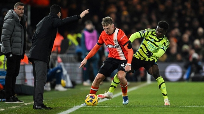 Manajer Luton Town dari Wales Rob Edwards (Kiri) juga manajer Arsenal selama Spanyol Mikel Arteta (kedua dari kiri) meninjau gelandang Arsenal #07 Bukayo Saka (kanan) kemudian gelandang Luton Town #45 Alfie Doughty (kedua dari kanan) berebut bola selama pertandingan pekan ke-15 Turnamen Inggris di dalam Kenilworth Road di tempat Luton, utara London pada 5 Desember 2023.JUSTIN TALLIS / AFP.