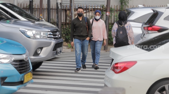 Pejalan kaki memakai masker saat melintas di kawasan Bundaran HI, Jakarta, Kamis (7/12/2023). [Suara.com/Alfian Winanto]