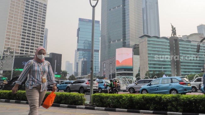 Pejalan kaki memakai masker saat melintas di kawasan Bundaran HI, Jakarta, Kamis (7/12/2023). [Suara.com/Alfian Winanto]