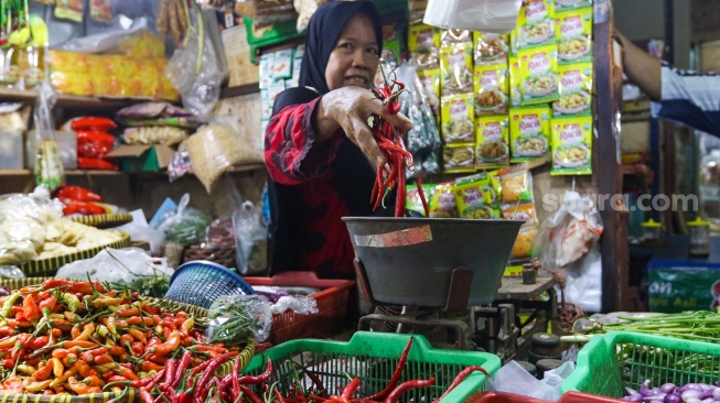 Pedagang menata cabai rawit dagangannya di pasar Cibubur, Jakarta, Kamis (7/12/2023). [Suara.com/Alfian Winanto]