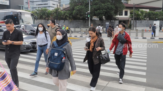 Pejalan kaki memakai masker ketika melintas pada kawasan Bundaran HI, Jakarta, Kamis (7/12/2023). [Suara.com/Alfian Winanto]