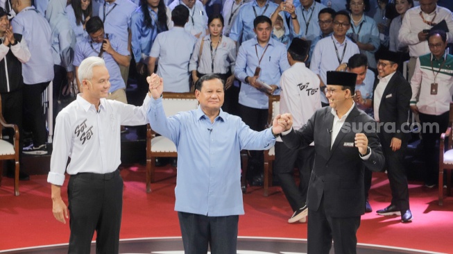 Capres nomor urut satu Anies Baswedan (kanan), Capres nomor urut dua Prabowo Subianto (tengah), Capres nomor urut tiga Ganjar Pranowo (kiri) saling berpegangan tangan usai debat perdana Capres dan Cawapres 2024 di Gedung KPU, Jakarta, Selasa (12/12/2023). [Suara.com/Alfian Winanto]