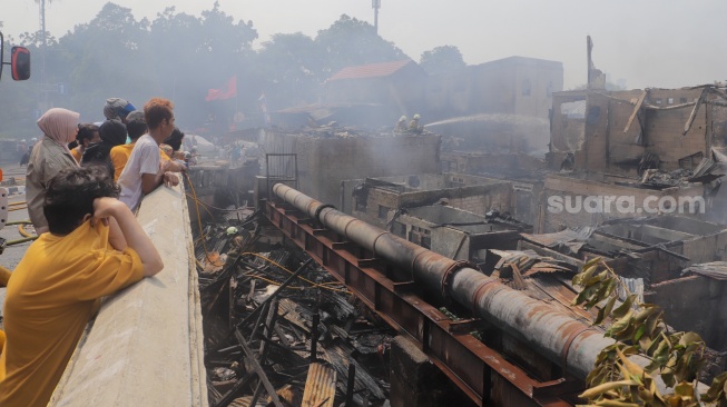 Warga melihat kebakaran di pemukiman padat di kawasan Manggarai, Tebet, Jakarta, Kamis (14/12/2023). [Suara.com/Alfian Winanto]