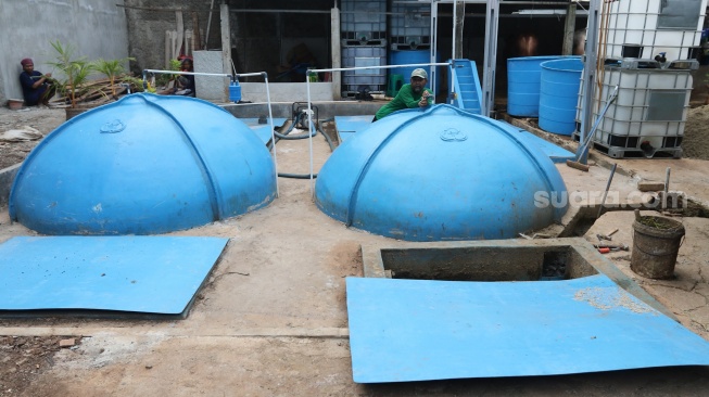 Pekerja memeriksa instalasi keran kontrol pada tangki biogas yang berasal dari limbah kotoran ternak di kawasan Pancoran, Jakarta, Jumat (15/12/2023). [Suara.com/Alfian Winanto]