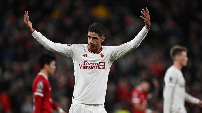 Bek Manchester United #19 Raphael Varane bereaksi ke arah para penggemar di akhir babak pertama pertandingan pekan ke-17 Liga Inggris antara Liverpool vs Manchester United di Anfield di Liverpool, barat laut Inggris pada 17 Desember 2023.Paul ELLIS / AFP.