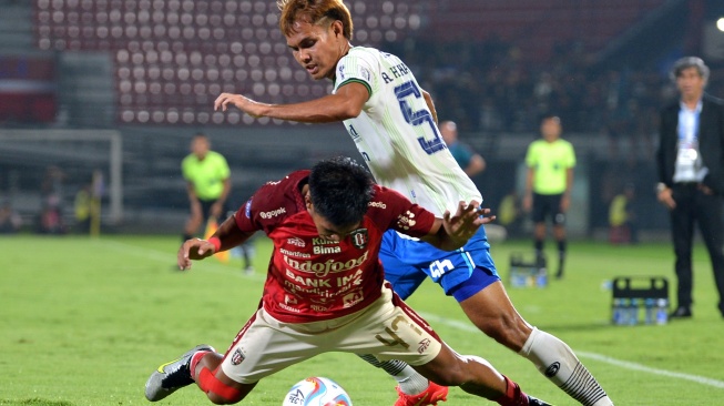 Pesepak bola Bali United Rahmat Arjuna (kiri) terjatuh saat berebut bola dengan pesepak bola Persib Bandung Rezaldi Hehanussa (kanan) saat pertandingan Liga 1 2023/2024 di Stadion Kapten I Wayan Dipta, Gianyar, Bali, Senin (18/12/2023). ANTARA FOTO/Fikri Yusuf/YU