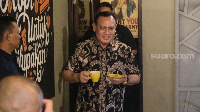 Ketua KPK nonaktif Firli Bahuri (tengah) berjalan sambil membawa kopi saat akan memulai konferensi pers di salah satu cafe di Jakarta Timur, Selasa (19/12/2023). [Suara.com/Alfian Winanto]