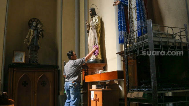 Petugas menyiapkan dekorasi dan membersihkan area Gereja Katedral, Jakarta, Kamis (21/12/2023). [Suara.com/Alfian Winanto]