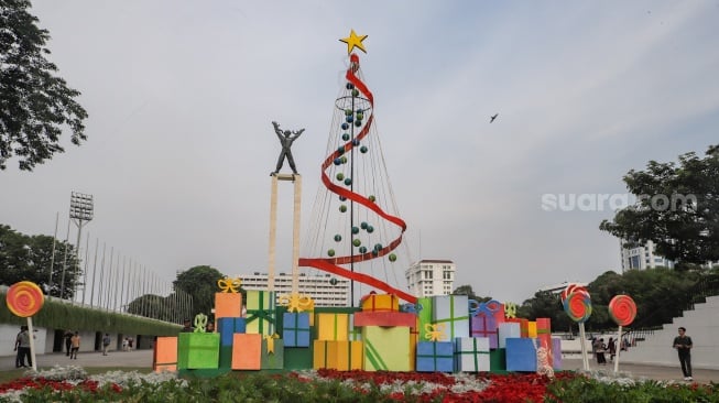 Sejumlah warga menghabiskan waktu liburan dengan bermain dan berfoto di depan dekorasi khas Natal di Taman Lapangan Banteng, Jakarta, Selasa (26/12/2023). [Suara.com/Alfian Winanto]