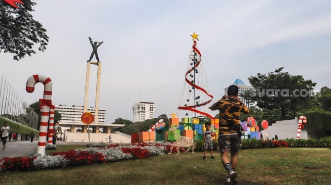 Sejumlah warga menghabiskan waktu liburan dengan bermain dan berfoto di depan dekorasi khas Natal di Taman Lapangan Banteng, Jakarta, Selasa (26/12/2023). [Suara.com/Alfian Winanto]