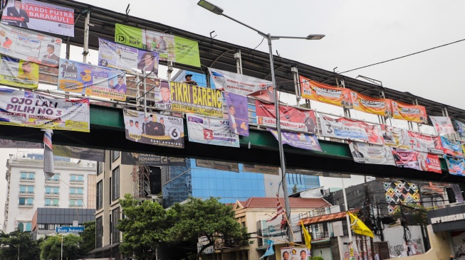 Kendaraan melintas di bawah Jembatan Penyeberangan Orang (JPO) yang tertutup oleh alat peraga kampanye Pemilu 2024 di Jakarta, Kamis (28/12/2023). [Suara.com/Alfian Winanto]