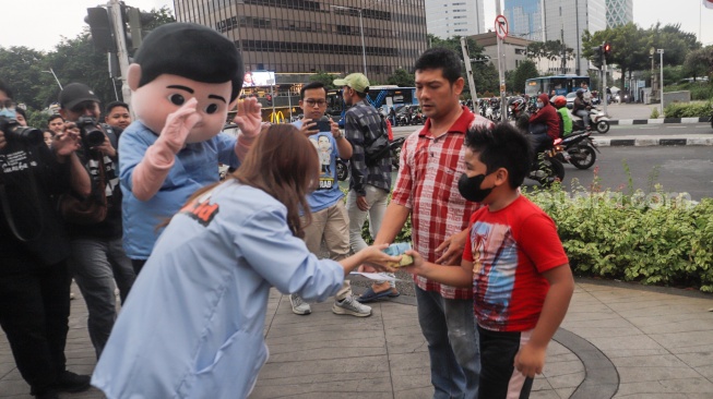 Boneka Gemoy Prabowo Subianto membagikan susu gratis kepada warga yang melintas di Perempatan Lampu Merah Sarinah, Jakarta, Jumat (29/12/2023). [Suara.com/Alfian Winanto]