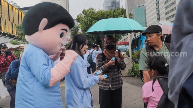 Boneka Gemoy Prabowo Subianto membagikan susu gratis kepada warga yang melintas di Perempatan Lampu Merah Sarinah, Jakarta, Jumat (29/12/2023). [Suara.com/Alfian Winanto]