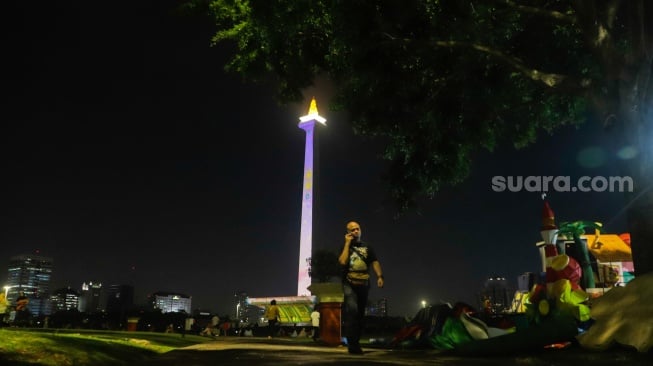 Pengunjung menyaksikan pertunjukan video mapping Monas Week di Monumen Nasional (Monas), Jakarta, Jumat (29/12/2023). [Suara.com/Alfian Winanto]