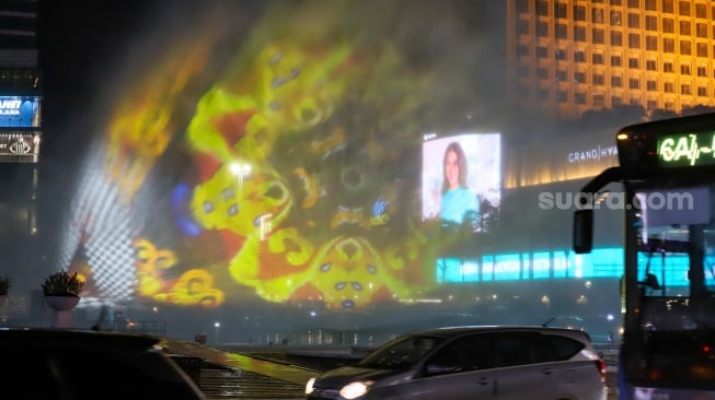 Warga menyaksikan water screen yang sedang di uji coba untuk perayaan malam tahun baru di Bundaran HI, Jakarta, Sabtu (30/12/2023). [Suara.com/Alfian Winanto]
