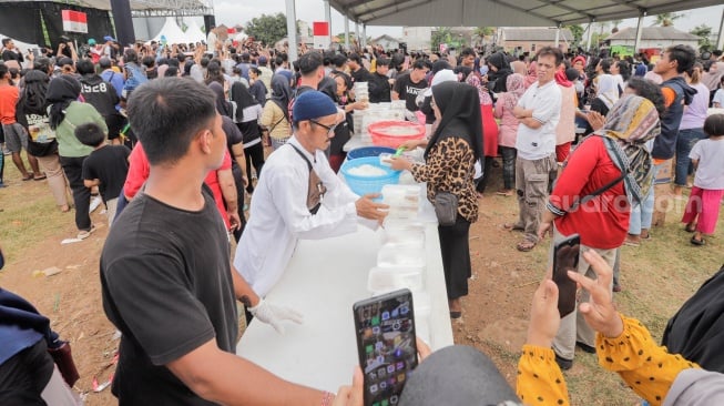 Warga membagikan makanan saat acara Masak Besar di Cilincing, Jakarta, Sabtu, (30/12/2023). [Suara.com/Alfian Winanto]